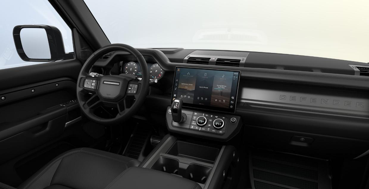 Land Rover Defender — Defender cabin with leather seats, exposed structural cross-beam, a floating centre console with cupholders and rotary climate controls.