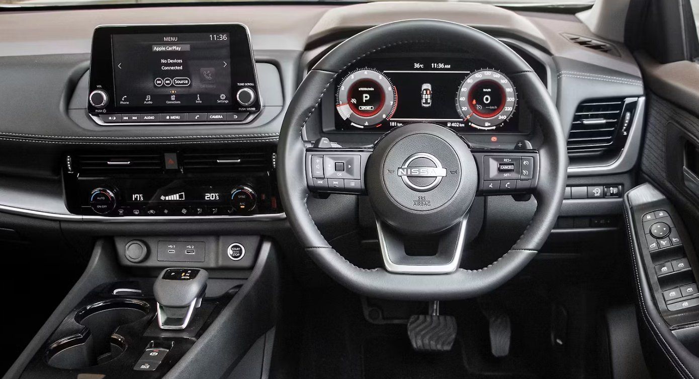 Nissan X-Trail interior showing steering wheel, digital dashboard, and infotainment screen.