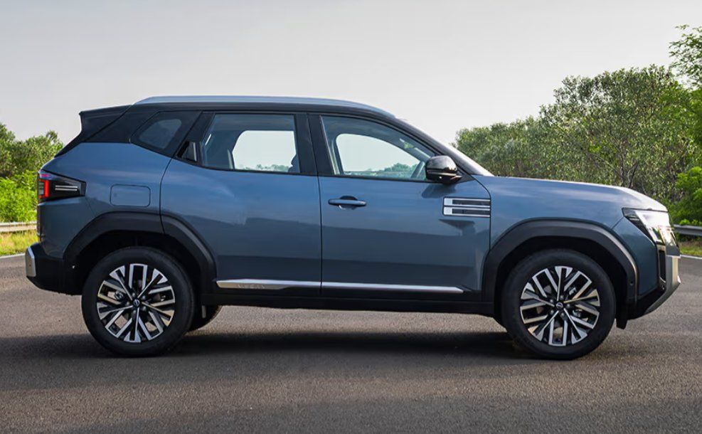 Blue SUV parked on road with trees in background, side view.