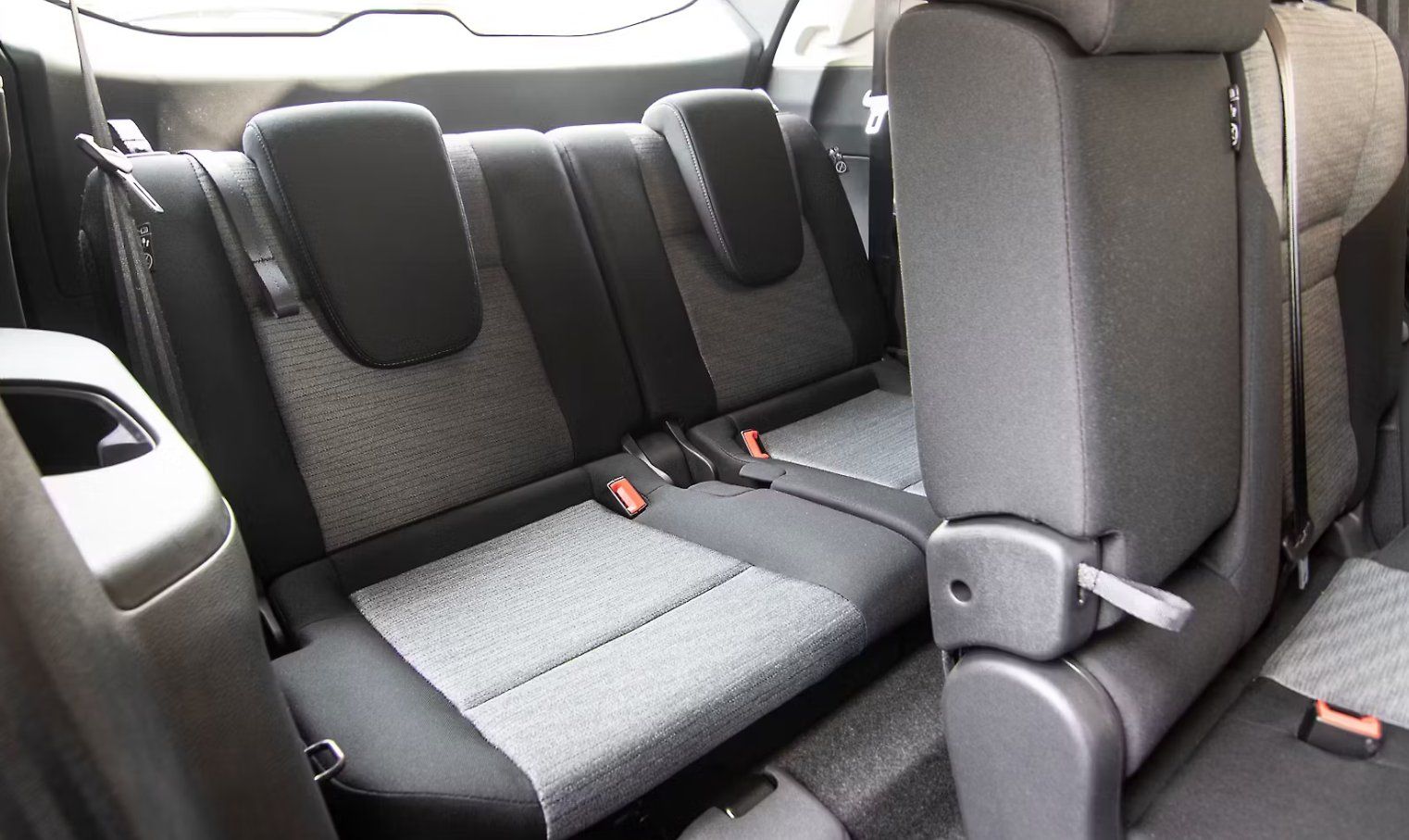Rear seat interior of vehicle with gray fabric upholstery and safety belts visible.