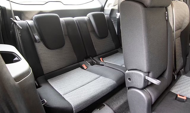 Rear seat interior of vehicle with gray fabric upholstery and safety belts visible.