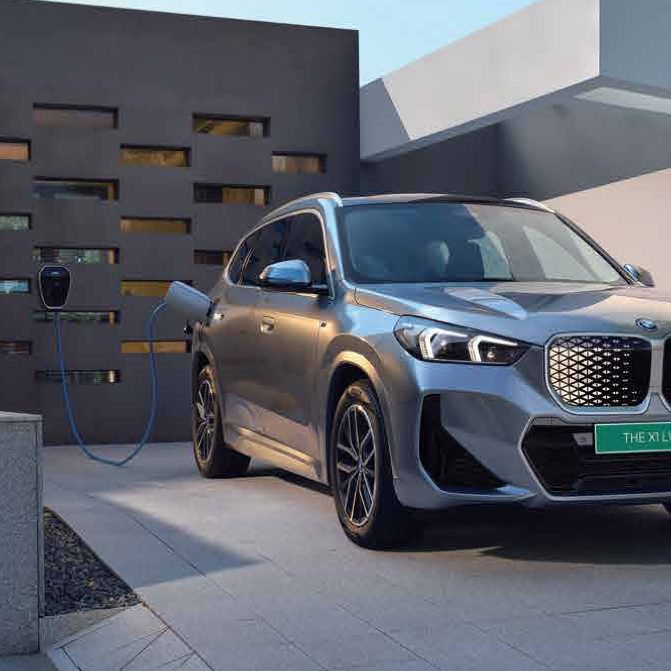 BMW iX1 LWB — BMW iX1 LWB charging at home, plugged into the wall-mounted BMW Wallbox