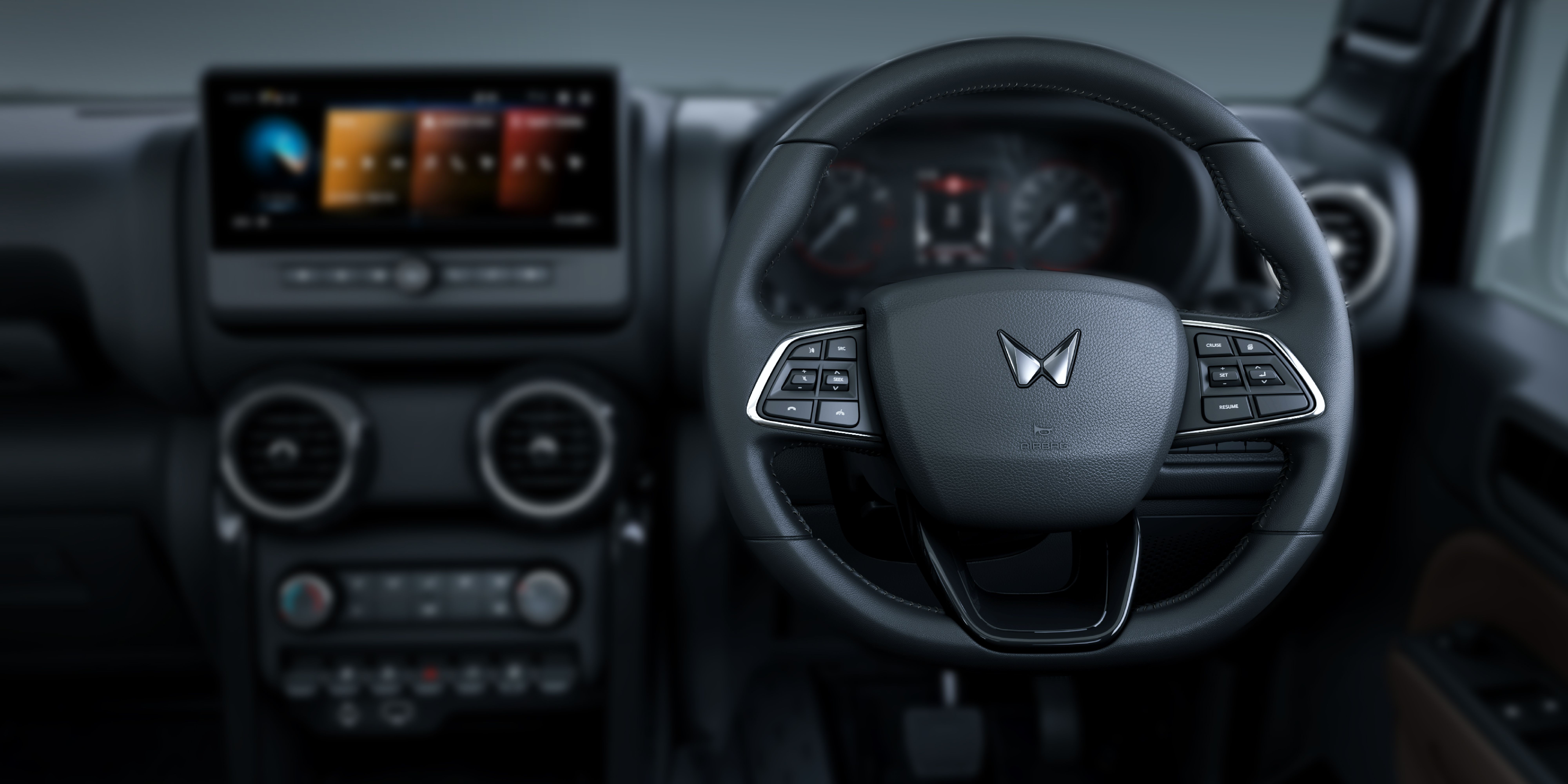 Mahindra Thar OG, Close view across the driver’s side of the cabin: leather-wrapped steering wheel with the Mahindra logo and both control