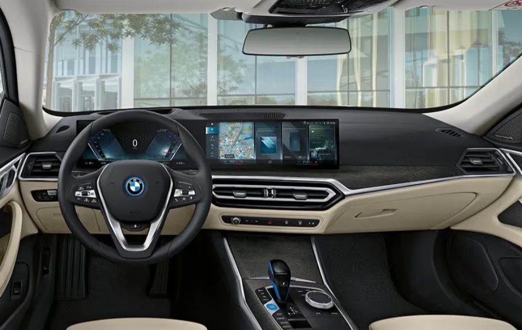 BMW i4 interior dashboard with digital display, steering wheel, and cream-colored trim.