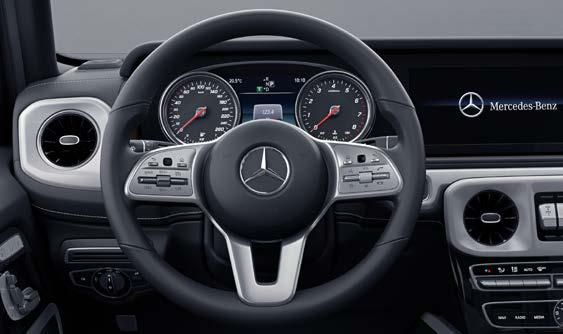 Mercedes-Benz G-Class — Multifunction sports steering wheel in nappa leather with chrome control panels, framing twin analogue-look instrument dials