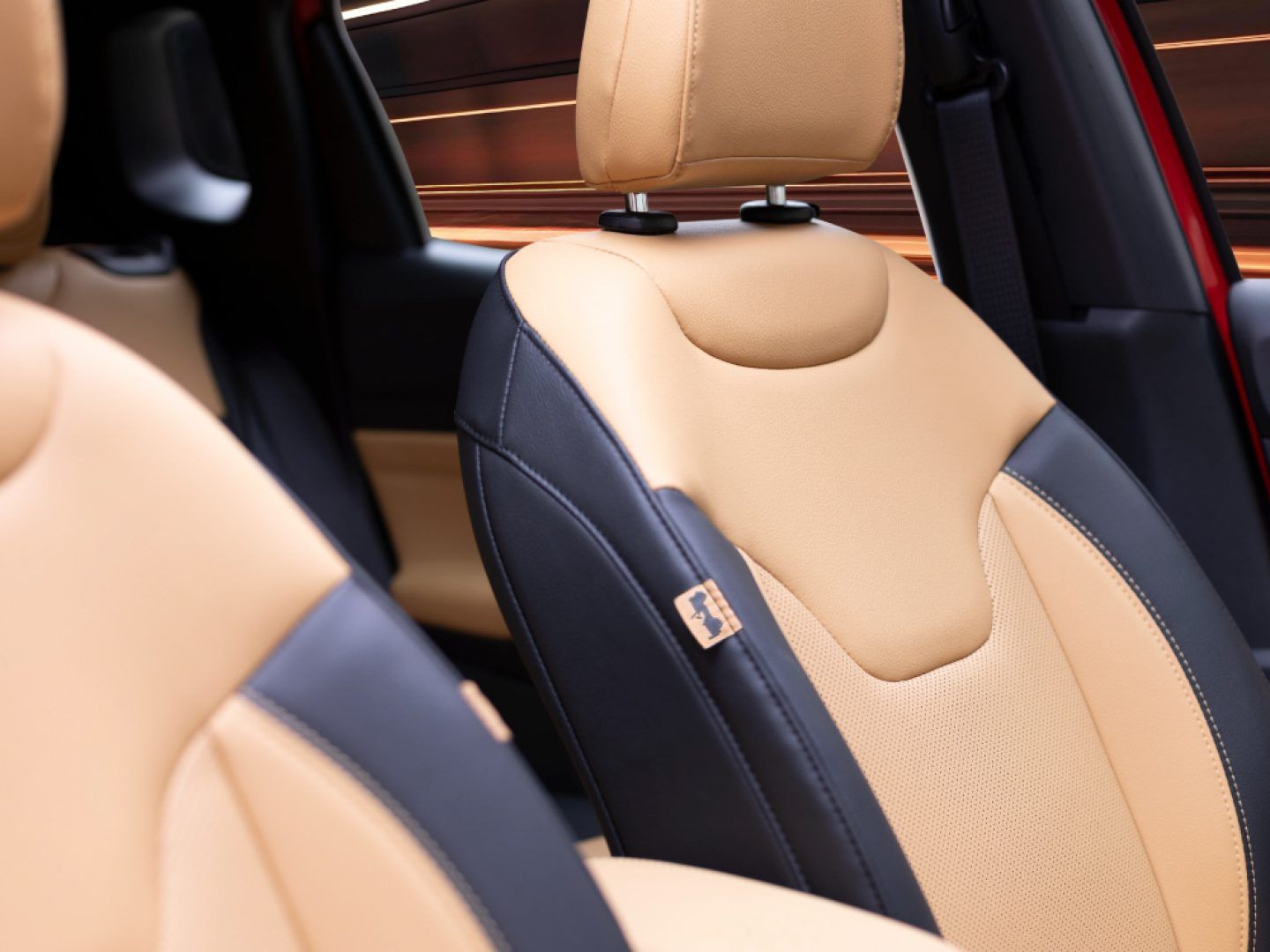 Jeep Compass — Two-tone tan-and-black leather upholstery with an embossed Jeep logo.