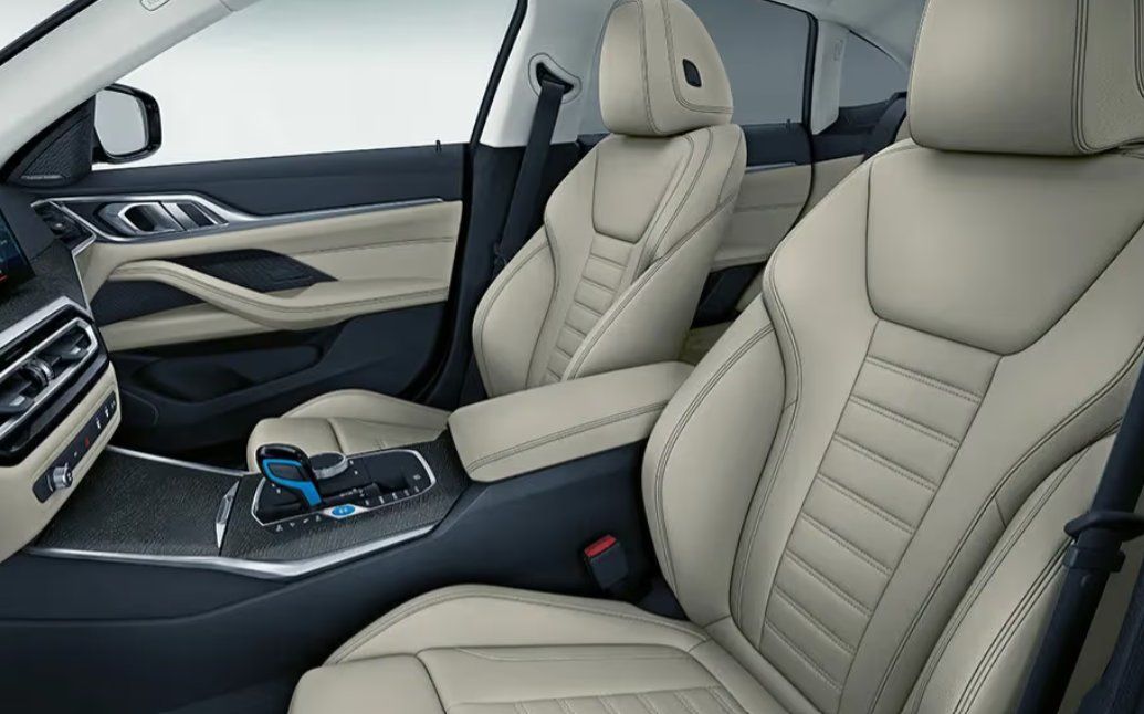Luxury car interior with cream leather seats and dark trim dashboard.