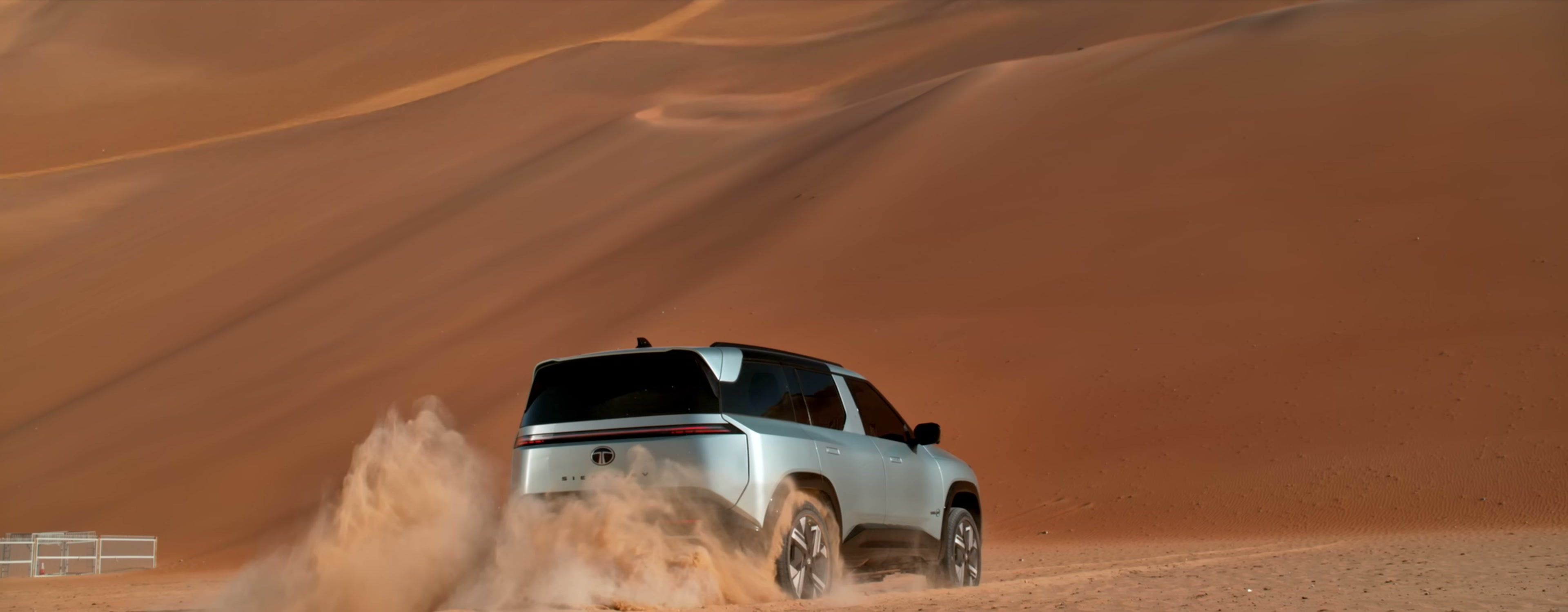 Tata Sierra.ev rear three-quarter view powering across desert sand