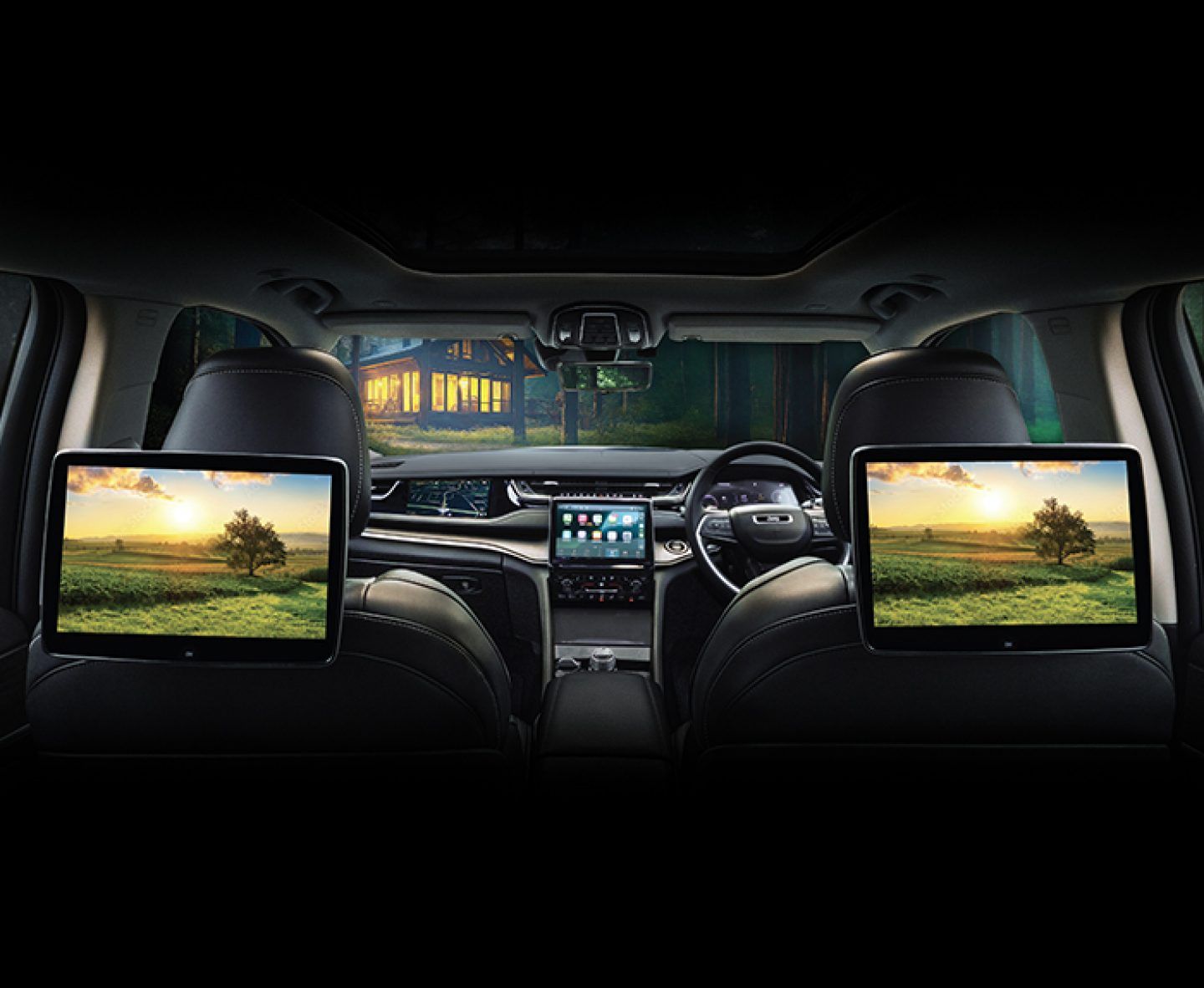 Jeep Grand Cherokee — Dual rear-seat entertainment screens mounted on the front headrests, with the dashboard touchscreen and driver display visible ahead.