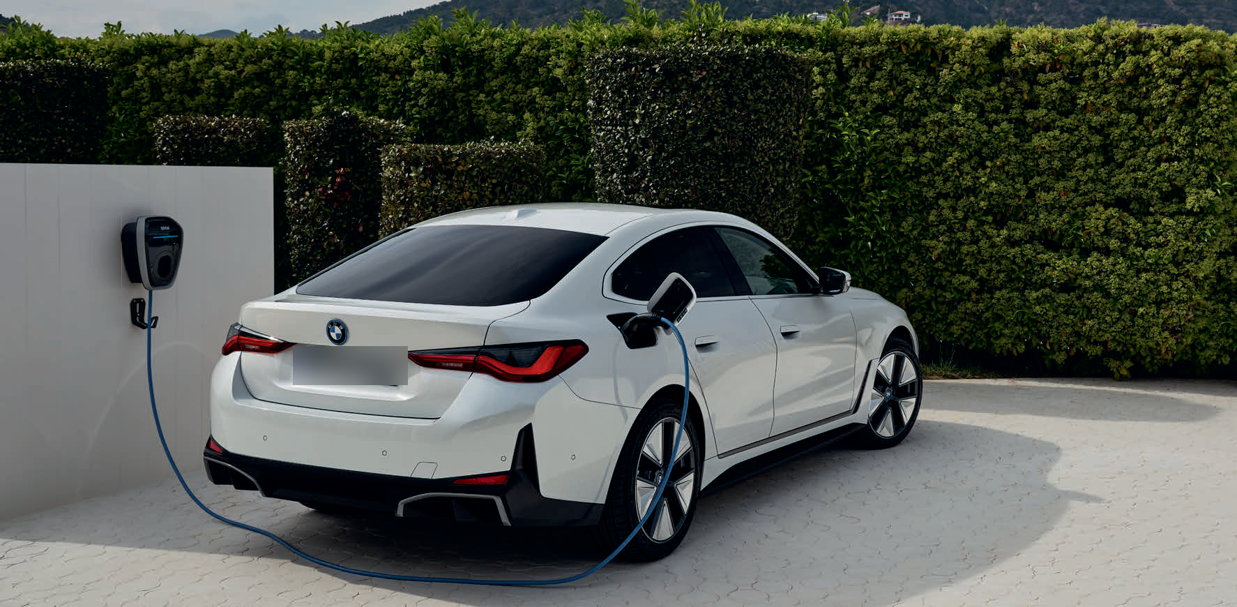 BMW i4 — Home AC charging via the wall-mounted BMW Wallbox, delivering up to 11 kW to the i4's side charging port.