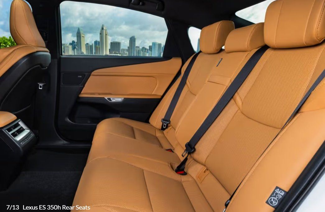 Luxury sedan rear interior with tan leather seats and city skyline view through window.