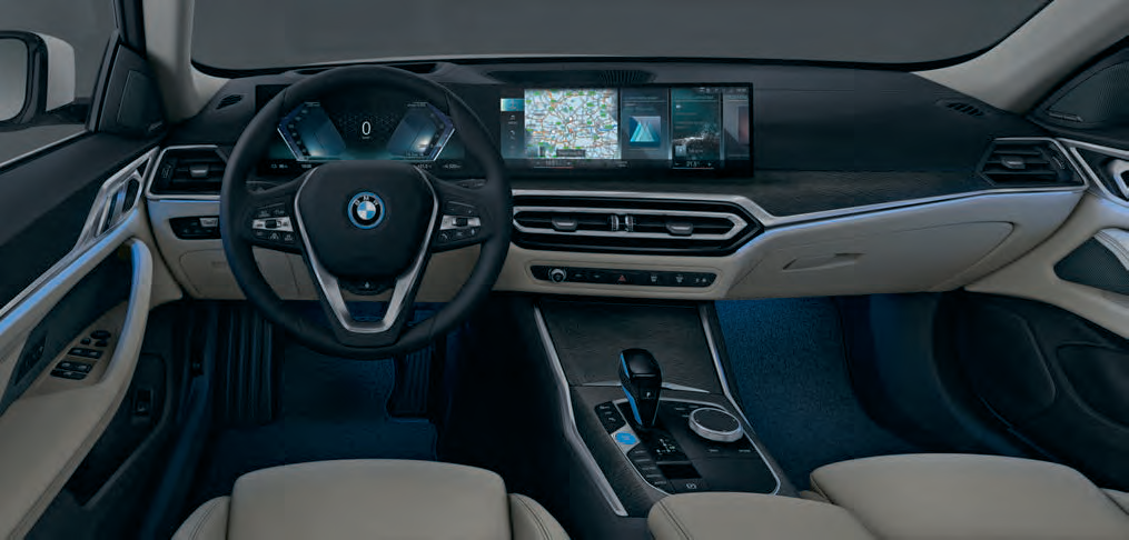 BMW i4 — Ambient interior lighting casts a blue contour glow across the doors and centre console at night.