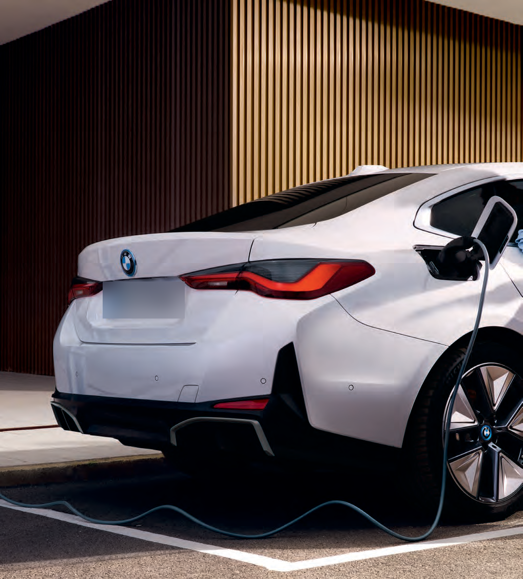 BMW i4 — Charging cable connected to the i4's rear side charging port, feeding the 83.9 kWh lithium-ion high-voltage battery.