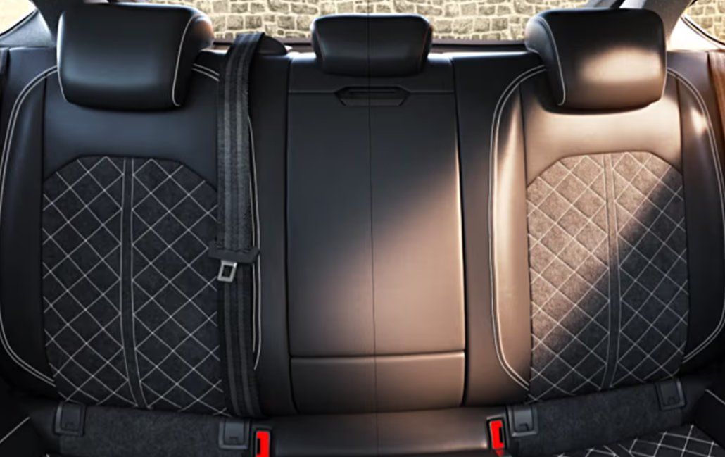 Rear car seats with black leather and quilted diamond pattern upholstery.