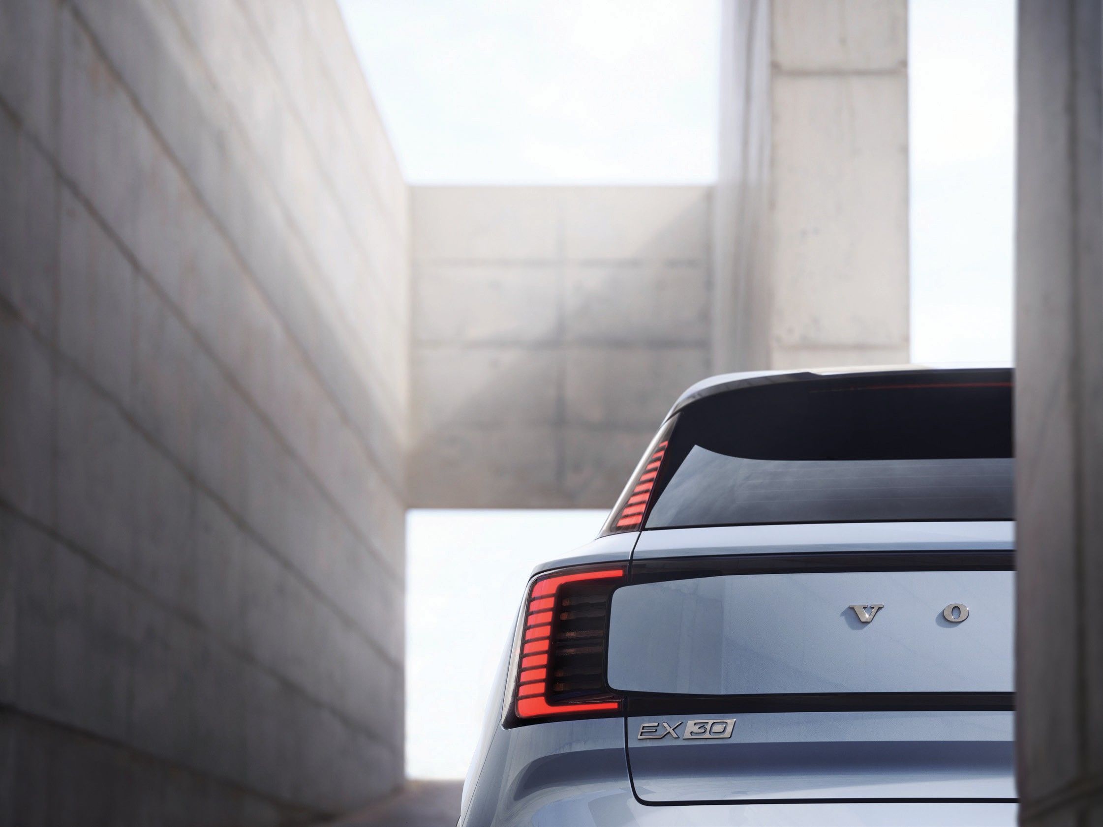 Volvo EX30 — Close-up of the vertical wraparound LED tail-light and roof spoiler at the rear tailgate.