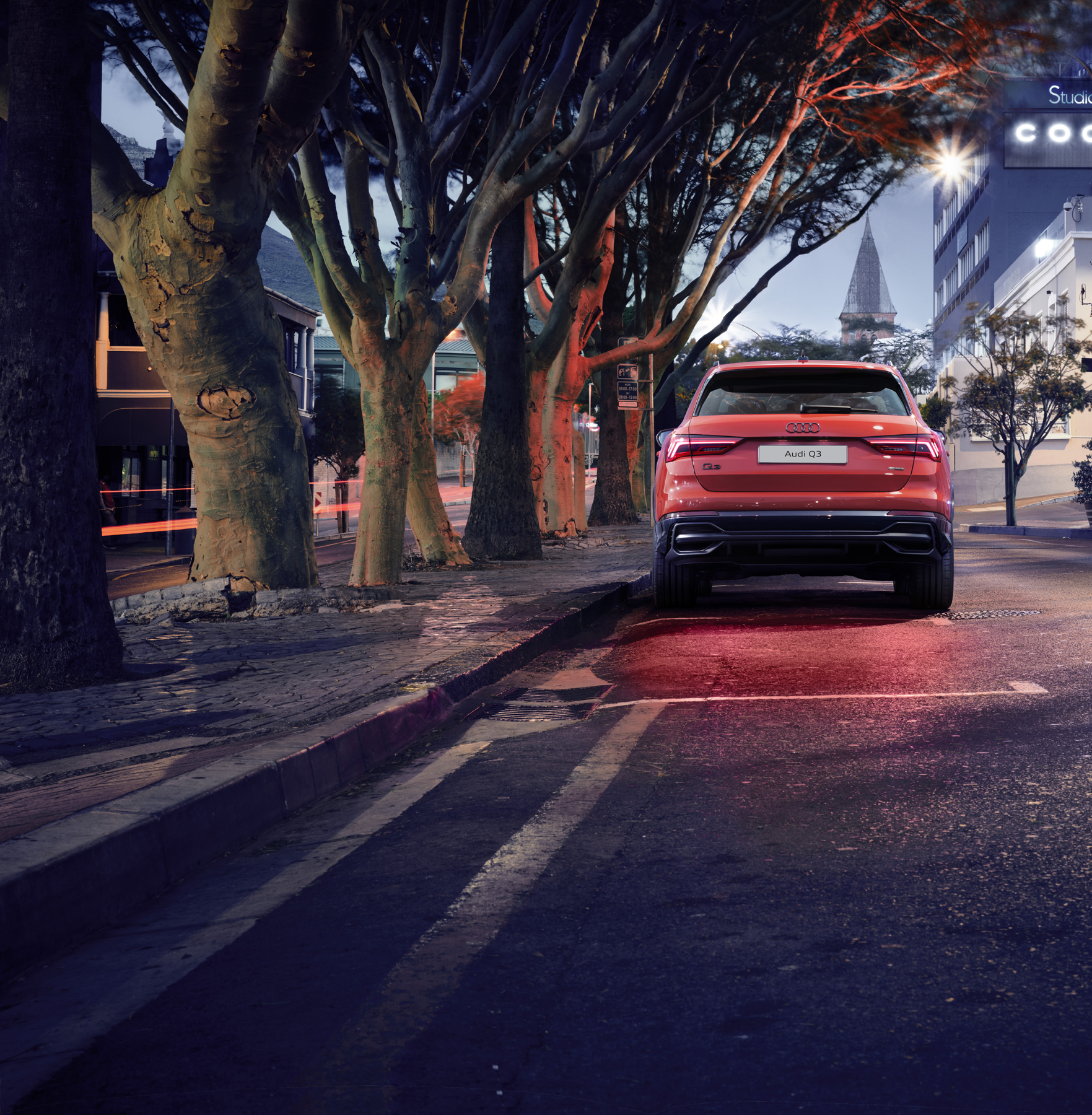 Audi Q3 — LED rear combination lamps illuminated across the tailgate at night.