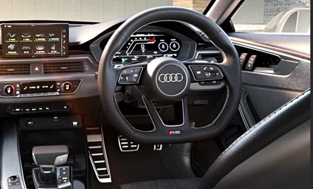 Audi RS5 interior with steering wheel, digital dashboard, and center console controls.