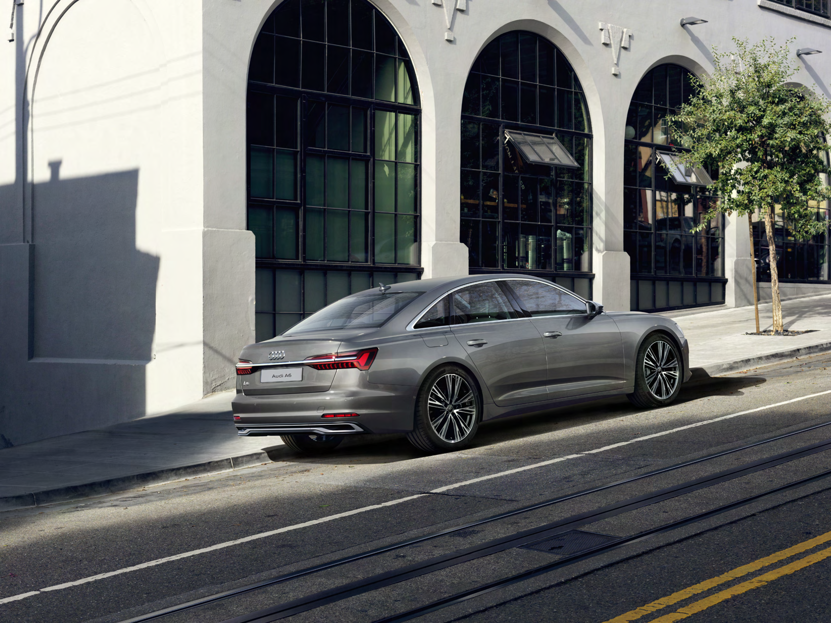Audi A6 — Rear three-quarter showing the coupe-like roofline and full-width LED tail-light strip