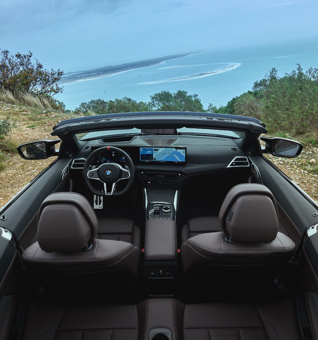 BMW M440i — Open-top cockpit view showing the two front sport seats, centre console and driver controls.