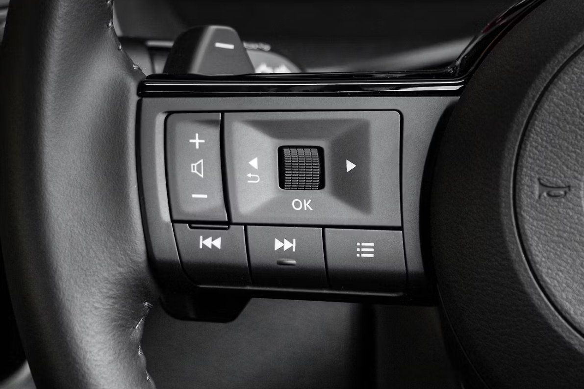 Steering wheel controls with audio and volume buttons in black and gray.