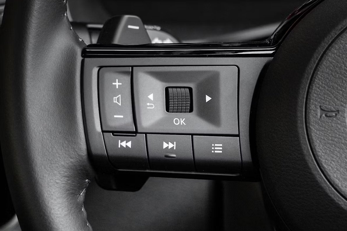 Steering wheel controls with audio and volume buttons in black and gray.