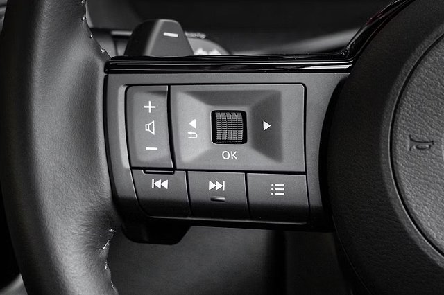 Steering wheel controls with audio and volume buttons in black and gray.