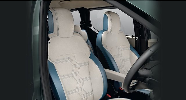 Front seats of a vehicle with cream and blue upholstery and geometric stitching patterns.