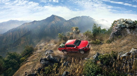 Toyota Hilux (2022-2025), Four-wheel-drive capability climbing a rugged mountain trail.