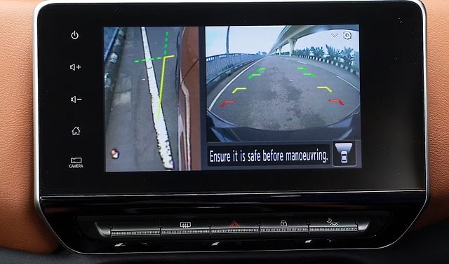 Rear-view camera display showing highway with distance guide lines and safety warning.