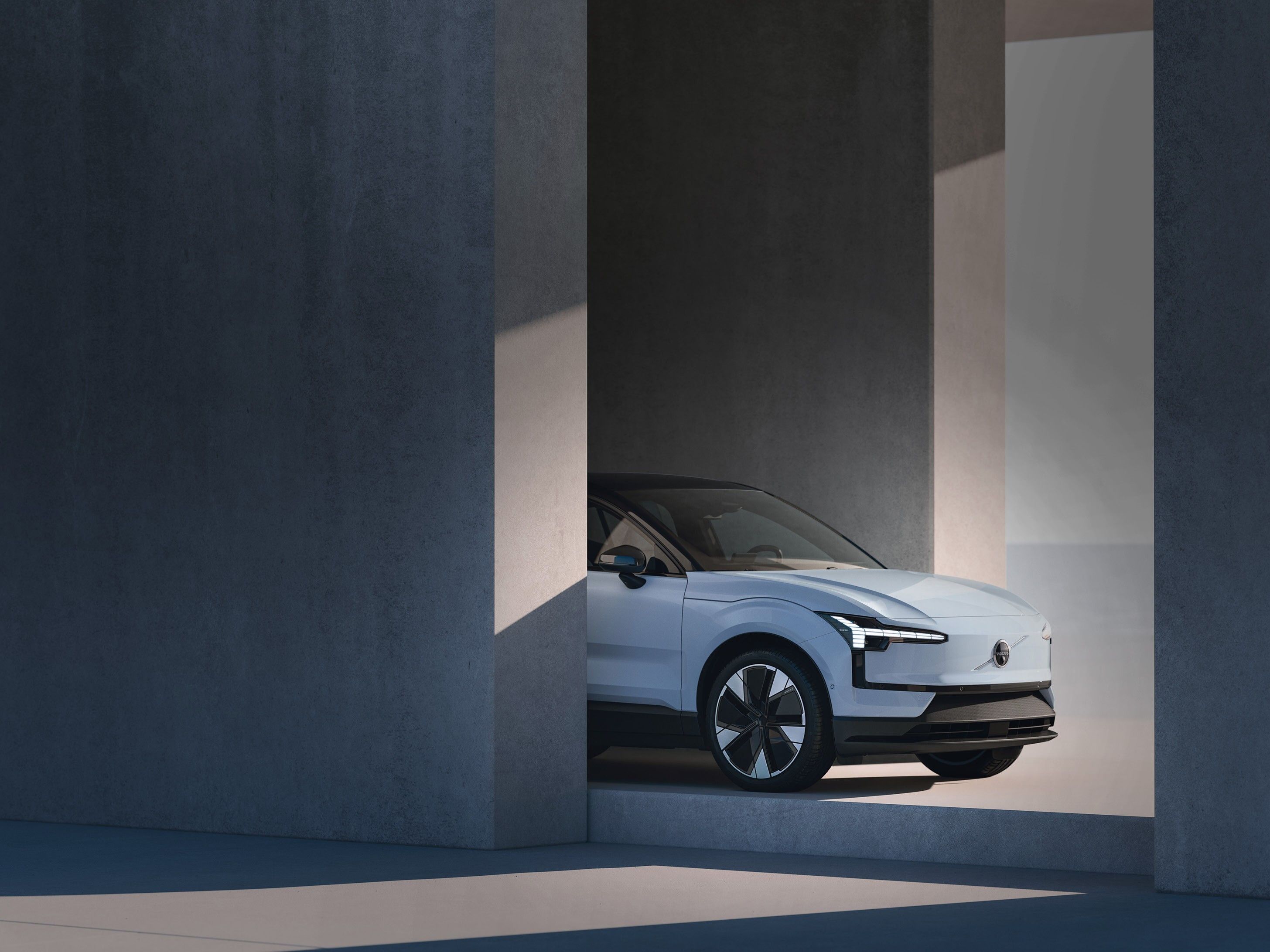 Volvo EX30 — Front three-quarter view showing the closed front panel, C-shaped LED headlights and aerodynamic alloy wheels.