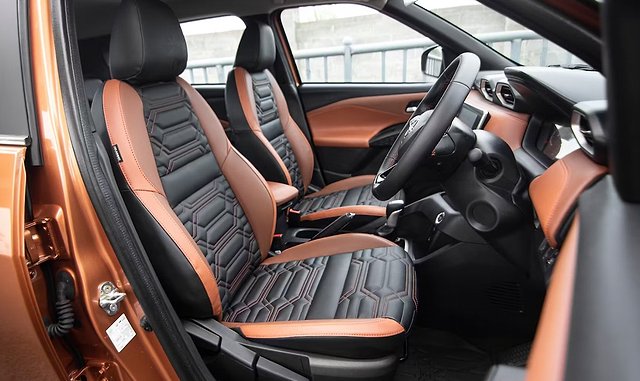 Orange and black leather car interior with steering wheel and dual front seats.