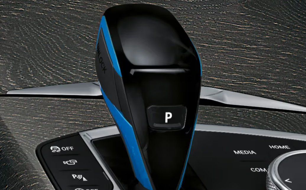 BMW i4 key fob with blue and black design next to dashboard controls.