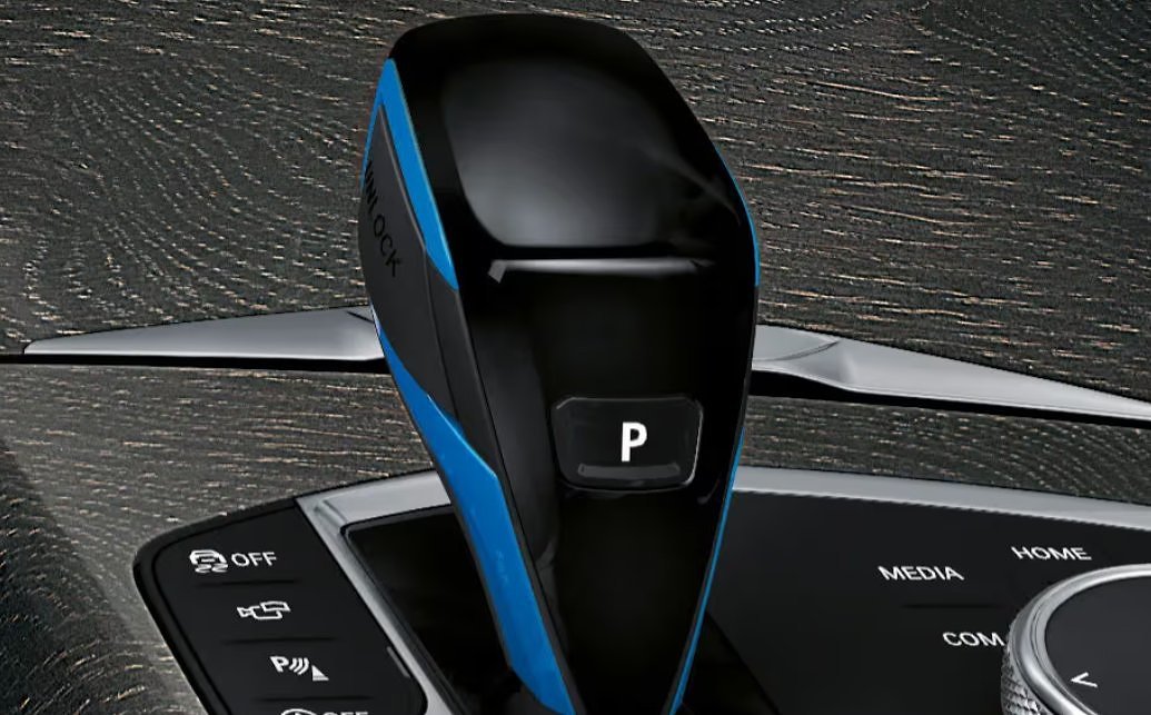 BMW i4 key fob with blue and black design next to dashboard controls.