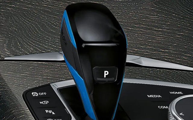 BMW i4 key fob with blue and black design next to dashboard controls.