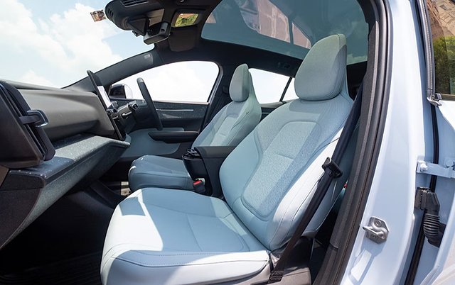 White compact electric car interior with light blue seats and panoramic sunroof.