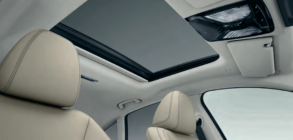 BMW i4 — Panoramic glass sunroof with electric sunshade brightens the cabin beneath the light beige headliner.