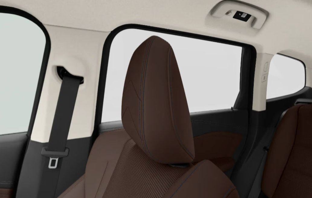 Rear car interior with brown leather seats, windows, and overhead controls.