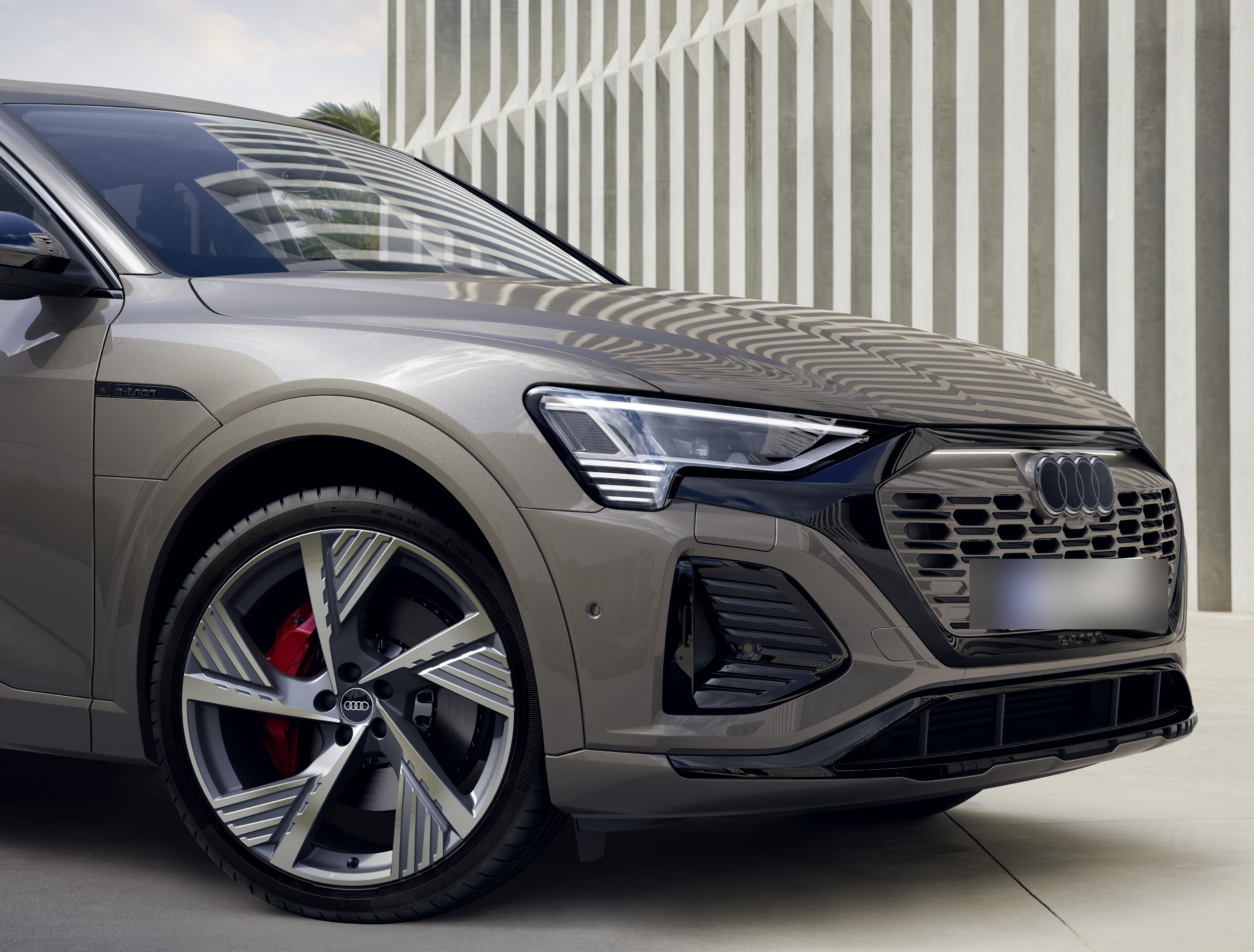 Audi Q8 e-tron — Aerodynamic Audi Sport alloy wheel with red brake calipers, framed by the sculpted front bumper.