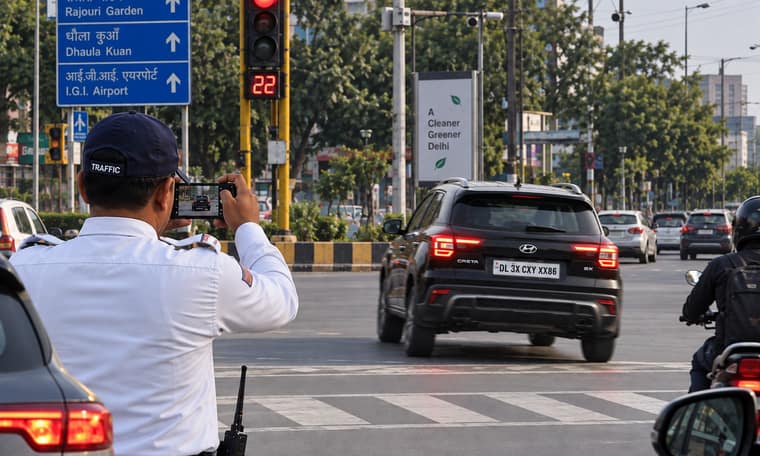 A traffic police officer photographing the number plate of a car at a Delhi junction